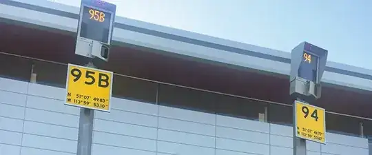 Image showing two airliner parking spots ("95B" and "94") at Calgary International Airport, Alberta, Canada. On the spot signs are GPS coordinates.