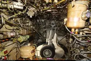 The insides of a 737 wheel well. Looking through the hole, we can see the wheel of the plane. On the inside, there are lots and lots of tubes and lines as well as other parts.