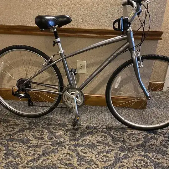 light grey-brown 3x bike with v-brakes and a fat cruiser-type saddle. The handlebars look very odd, but are not clear in the picture.