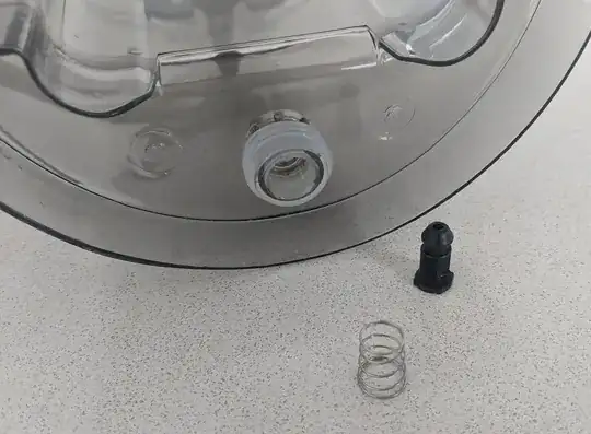 Image of the bottom of the water jug, the black screw and the spring.