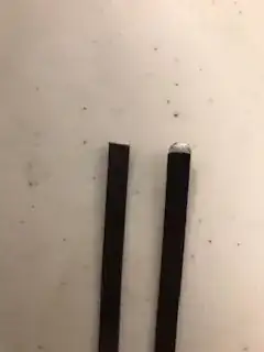 Two flat metal wires. One is cut straight and the other has been rounded by a grinder.