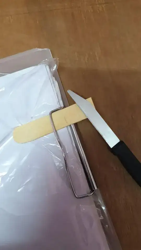 Picture of popsickle stick fixed in the clipboard and the serrated knife