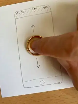 Sketch of an iPhone with a gold wedding ring on the 'screen'. The tip of a finger is placed inside the ring, and arrows indicate it's being moved up and down.