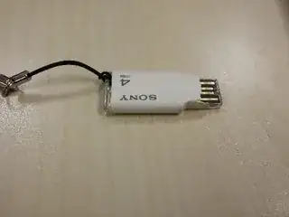 picture of the broken flash drive; the plastic casing that should cover the metal ribbons has snapped off unevenly