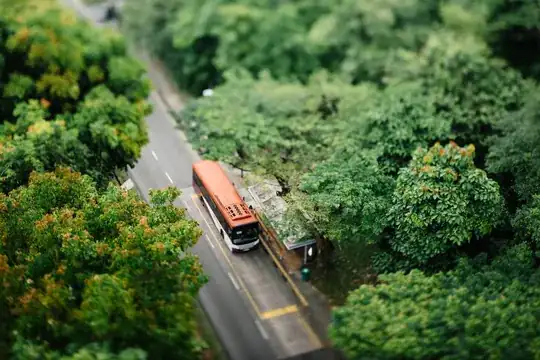 selective focus photo of orange and white bus surrounded with trees photo