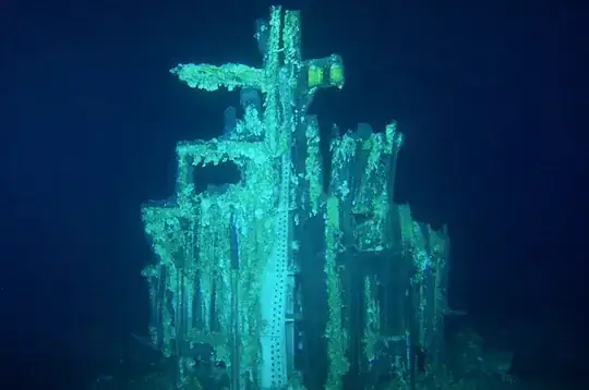 portion of Saturn V first stage, apparently upright on the ocean floor, partially covered in coral growth