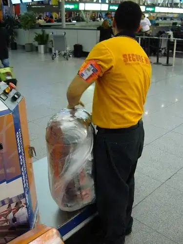 Wrapping luggage in plastic at JFK airport, USA