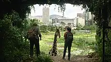 Joel and Ellie face a giraffe, which is standing in a large, grassy field.